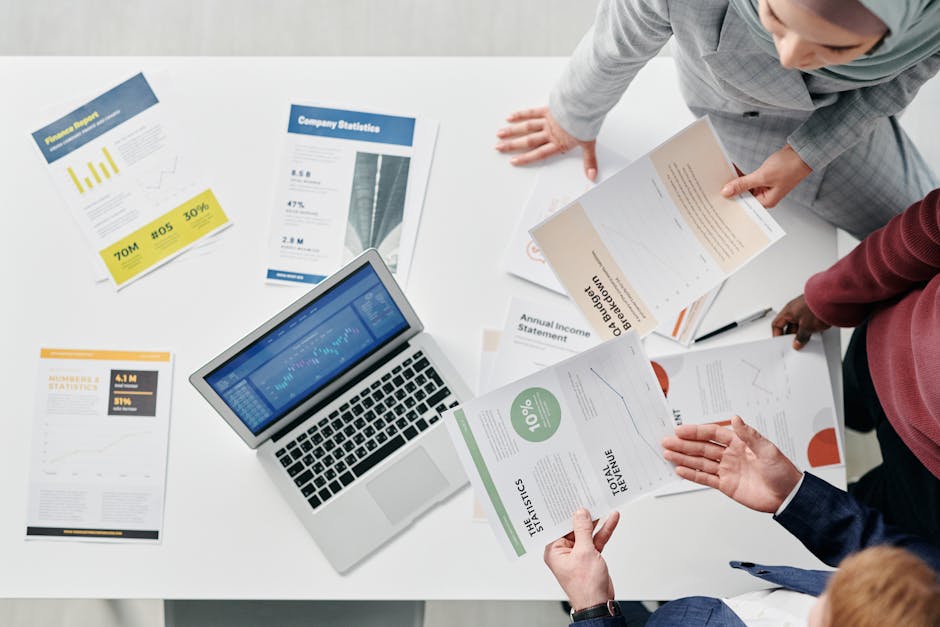 Top view of a professional office meeting with documents and laptop on the table.